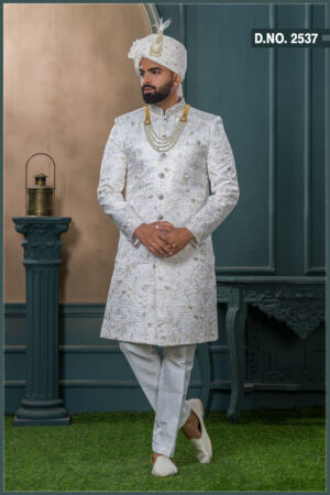 Ivory silk sherwani with golden thread and pearl embroidery, paired with an ivory turban featuring feather detailing and layered pearl mala.