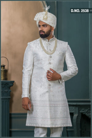 Ivory textured sherwani with silver and pink embroidery, paired with an ivory turban embellished with pearls and a feather accent.