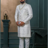 Ivory textured sherwani with silver and pink embroidery, paired with an ivory turban embellished with pearls and a feather accent.
