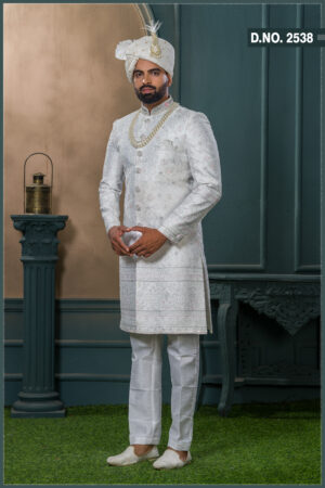 Ivory textured sherwani with silver and pink embroidery, paired with an ivory turban embellished with pearls and a feather accent.