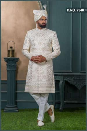 Ivory sherwani with intricate resham and sequin embroidery in floral and geometric patterns, paired with an ivory turban featuring pearl and feather embellishment.