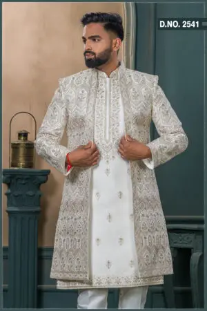Ivory beige sherwani featuring geometric and floral embroidery with pink accents, paired with a white inner kurta and churidar.